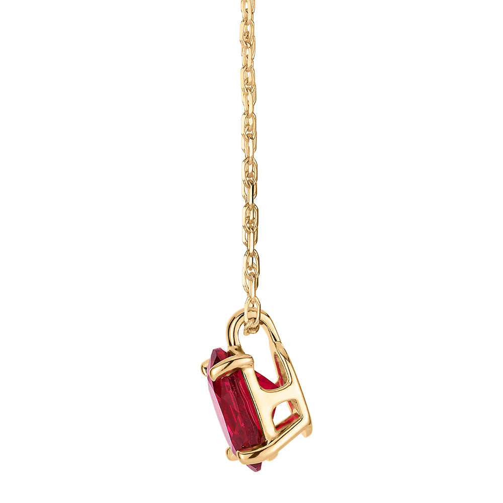 Oval solitaire necklace with ruby simulant in 10 carat yellow gold