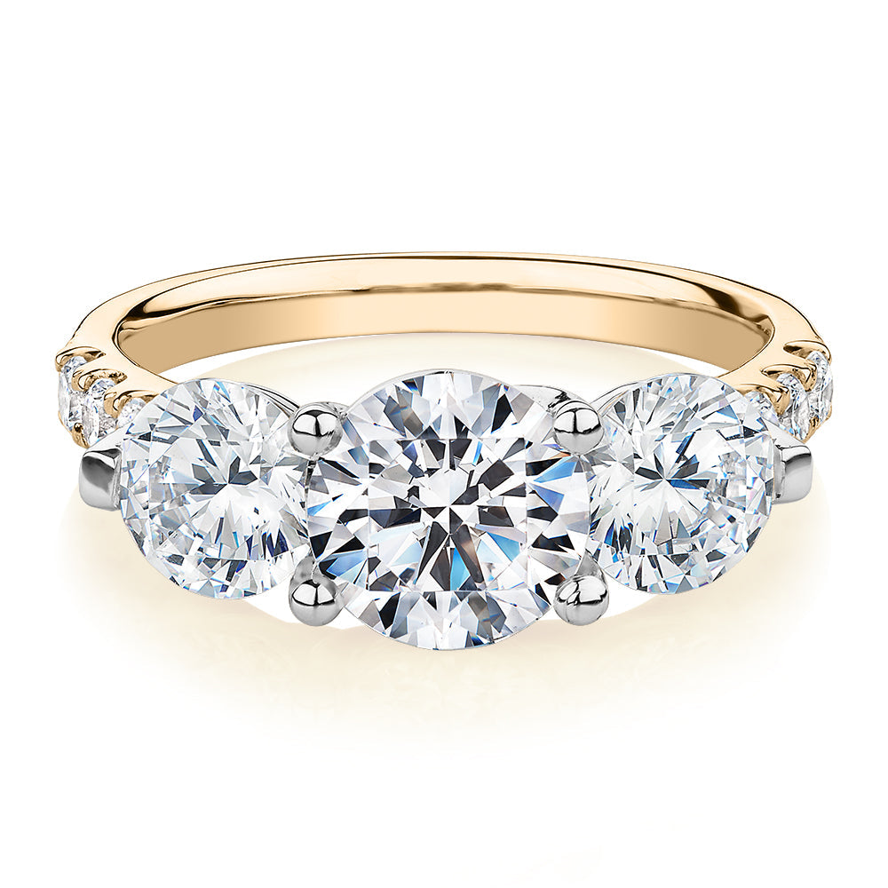 Three stone ring with 3.59 carats* of diamond simulants in 10 carat yellow and white gold